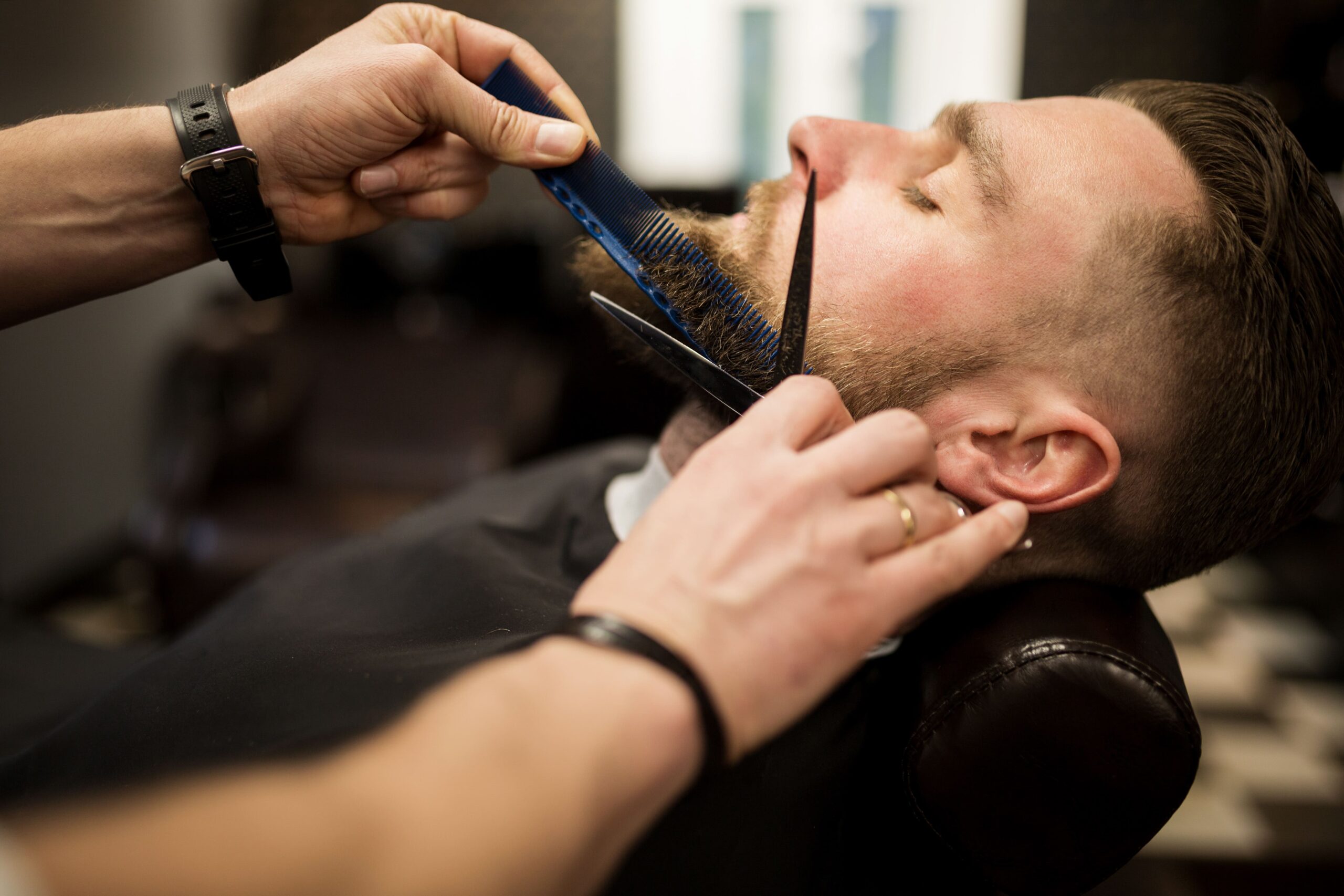 A man having his beard trimmed at the barber.