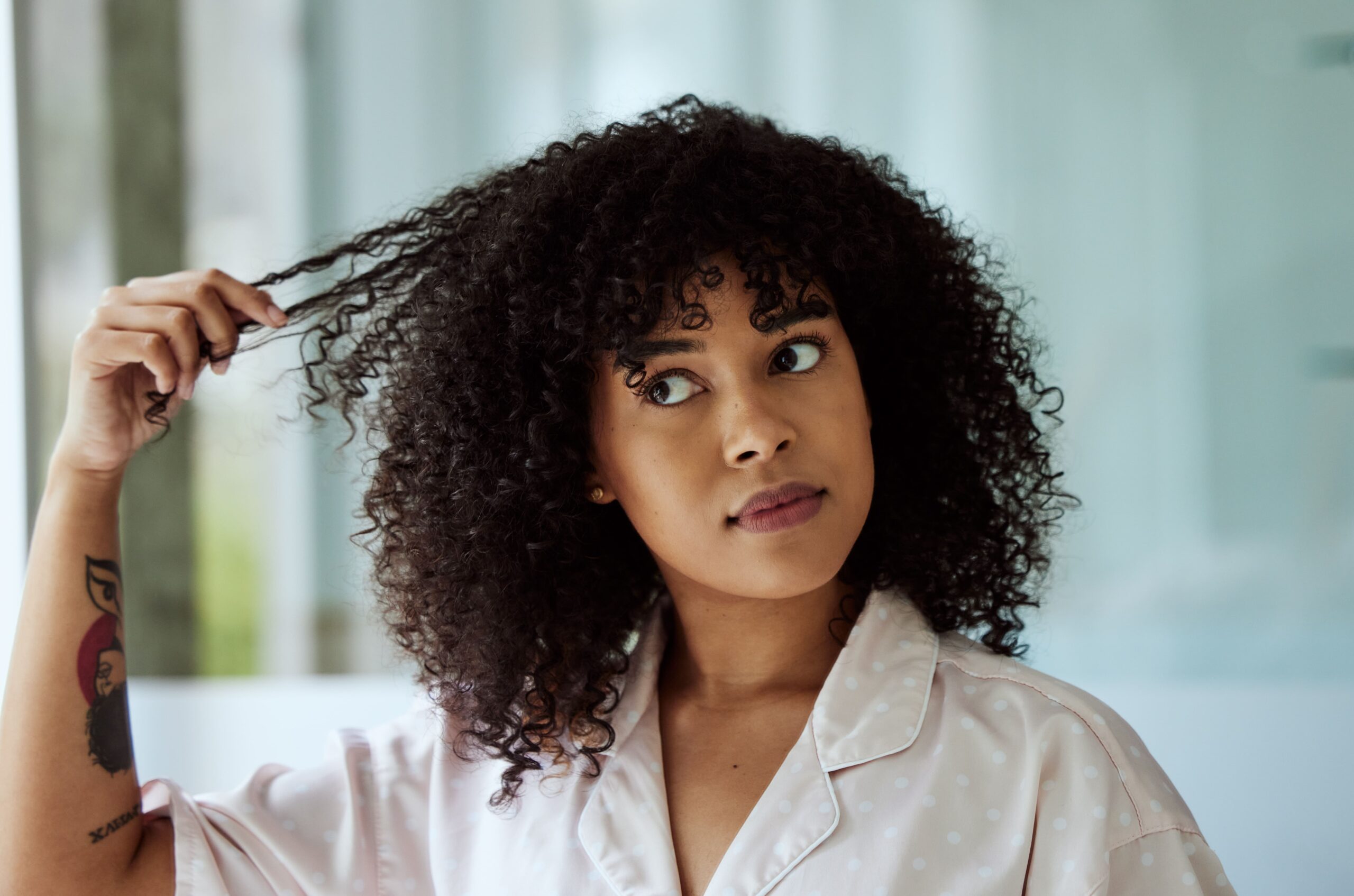 A woman touching her curly hair.